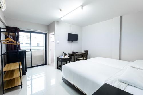 a white bedroom with a bed and a desk at Annex Lumpini Bangkok in Bangkok