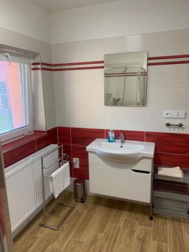 a bathroom with a white sink and red and white stripes at Apartmány Vinařství Tesařík in Prušánky