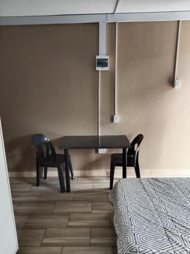 a room with a table and two chairs and a bed at AMASHIYA flats in Richards Bay