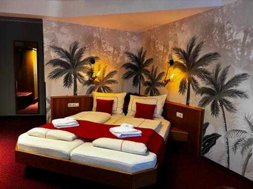 a bedroom with a bed with palm trees on the wall at Ambiente Hotel Strehla in Strehla