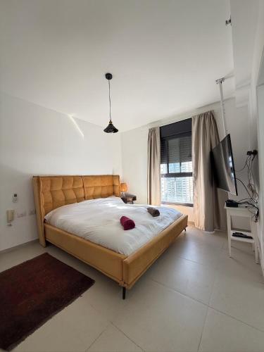 a bedroom with a large bed and a flat screen tv at שלוות העמק - דירת 3 חדרי שינה במיקום מרכזי in Ganne Tiqwa