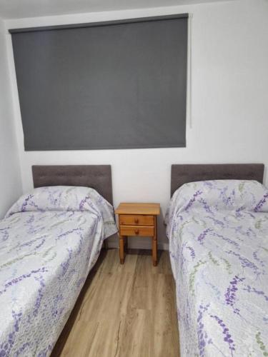 two beds in a room with a table between them at Mirada Ponent in Es Pujols