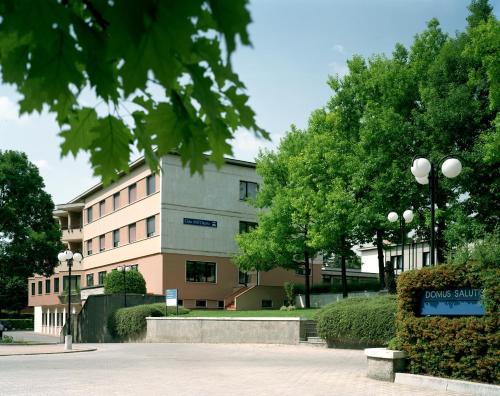un edificio de oficinas con árboles delante de él en Albergo Casa dell'Ospite en Brescia