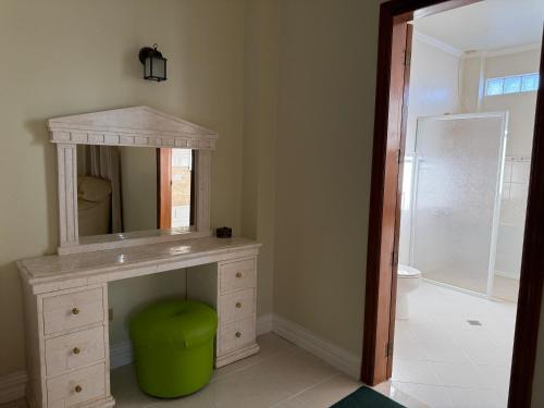 ein Badezimmer mit Waschtisch, Spiegel und grünem Hocker in der Unterkunft Mateos Villa in Carmen