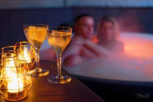 a man in a bath tub with champagne glasses on a table at Domaine 10 in Schore