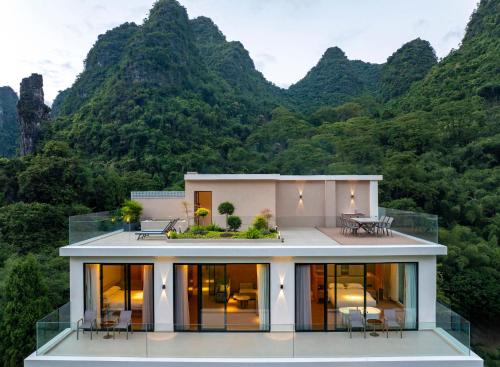a house with mountains in the background at Yangshuo Xishan Resort in Yangshuo