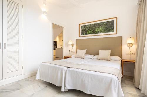 a white bedroom with a large bed with white sheets at Parque Santiago IV Official in Playa de las Americas