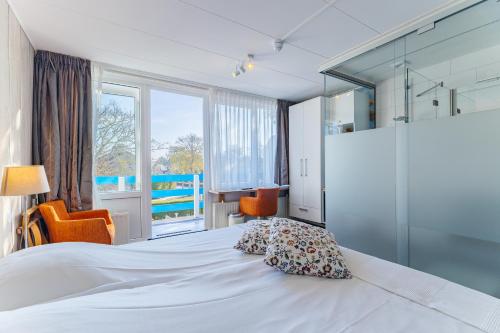 a bedroom with a bed and a large window at Hotel Kijkduin in Domburg