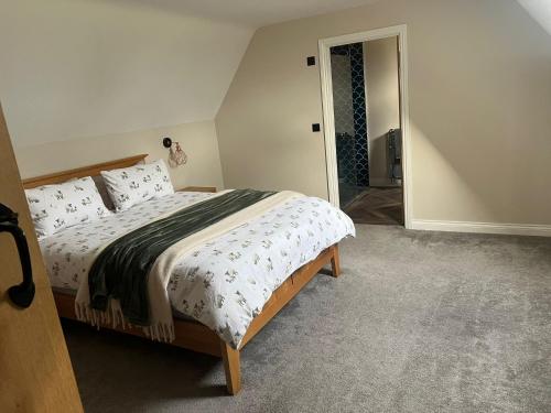 a bedroom with a bed and a door to a bathroom at Fallow View - Luxury Countryside Cottage in Coughton