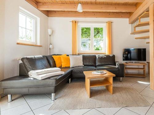 a living room with a black leather couch and a table at Ferienhof Rummel Allgäu - verschiedene Unterkünfte für bis zu 6 Personen - Sauna, Spielplatz, Lagerfeuer & Frühstücksservice - ideal für Familien- und Aktivurlaub in Argenbühl