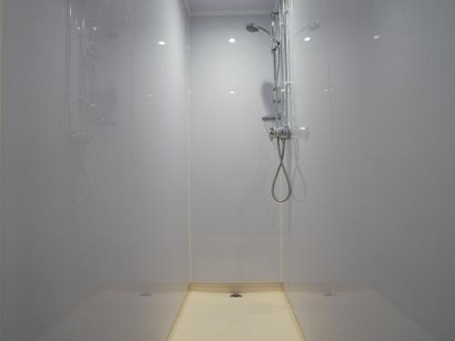 a shower in a bathroom with a white wall at YHA Whitby in Whitby