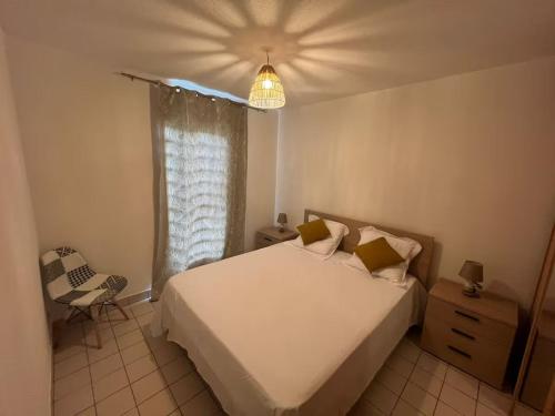 a bedroom with a white bed and a chair at Appartement tout confort et idéalement situé in Petit-Bourg