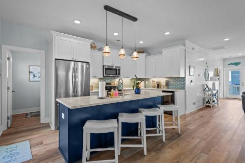 a kitchen with white cabinets and a blue island with bar stools at Ocean Views with Heated Pool One Row from Beach in Oak Island