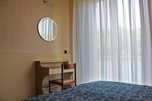 a bedroom with a bed and a chair and a mirror at Hotel Royal in Misano Adriatico