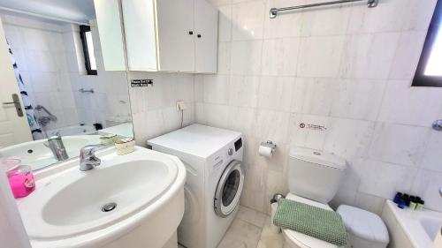 a bathroom with a toilet sink and a washing machine at Pasha Bay Residence in Sounio