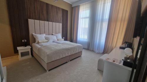 a bedroom with a bed and a large window at Pensiunea Casa Mitus in Strehaia