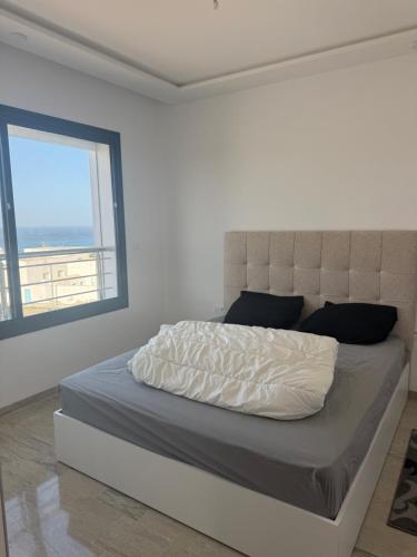 a white bedroom with a large bed with a large window at La chebba plage in Chebba
