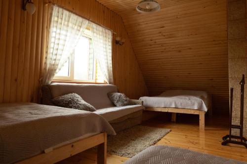 a bedroom with a couch and a window in a wooden room at Sodyba "Baltalaukis" in Didžiosios Kabiškės