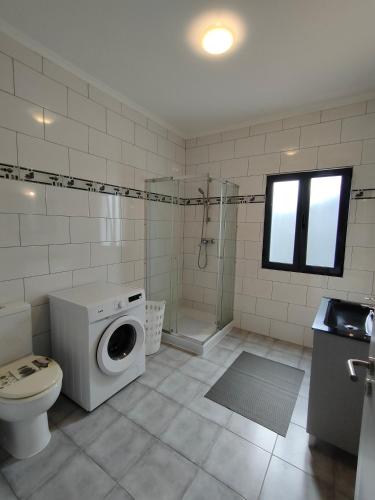 a bathroom with a toilet and a washing machine at Quinta Velha in Ribeira Grande