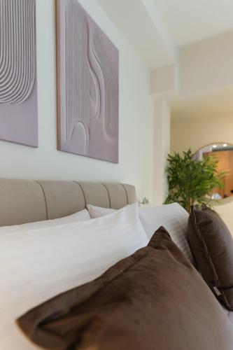una camera da letto con un letto con lenzuola bianche e una pianta di Opus Boutique Apartment a Alexandroupoli