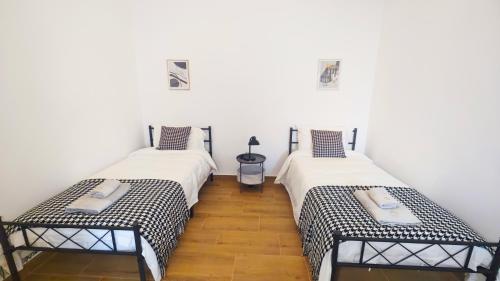 two beds in a room with white walls and wooden floors at Cascais Garden House 101 in Cascais