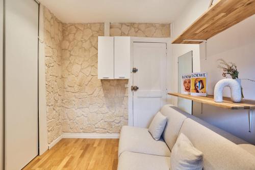 a living room with a couch and a stone wall at Charming Studio Arc de Triomphe Monceau in Paris