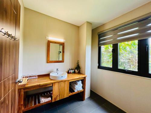 a bathroom with a sink and a mirror and a window at Ancarine Beach Resort in Phú Quốc