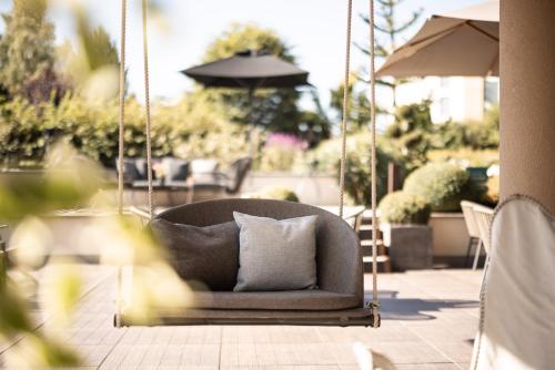 a couch swinging on a patio with an umbrella at DER MESNERWIRT - 4 Superior - Meraner Land in Avelengo