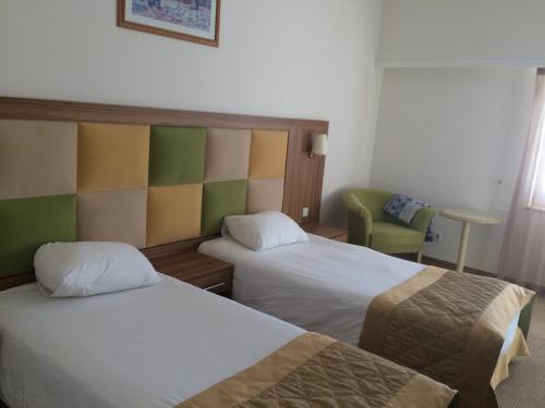 a hotel room with two beds and a chair at Palan Ski & Convention Resort Hotel in Erzurum