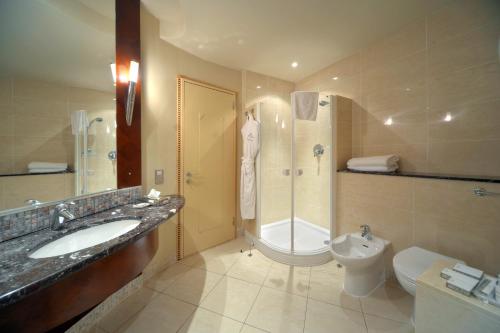 a bathroom with a sink and a shower and a toilet at Corinthia Tripoli in Tripoli