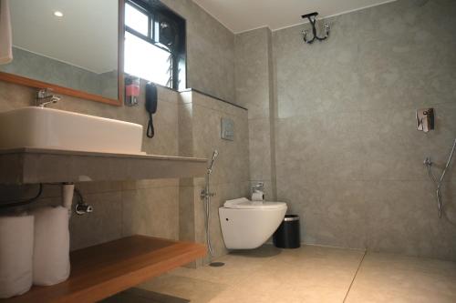 a bathroom with a white toilet and a sink at Brahmaputra Manor in Tezpur