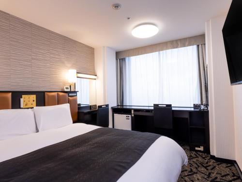 a hotel room with a bed and a desk and a window at APA Hotel & Resort Tokyo Bay Makuhari in Chiba