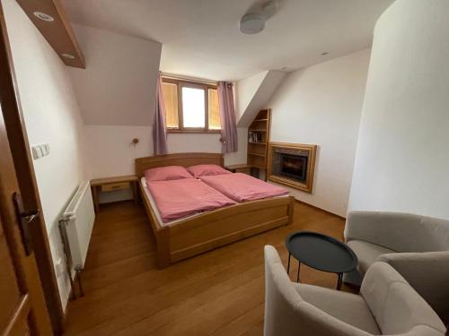 a small bedroom with a pink bed and a chair at Vinný sklep Tesařík in Prušánky