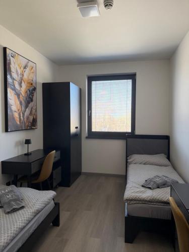 a room with two beds and a table and a window at Mayor Pension in Komárno
