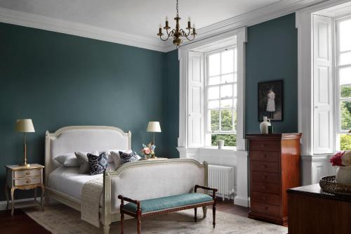 a bedroom with a bed and a chair and windows at Dripsey Castle Estate in Dripsey