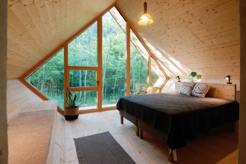 a bedroom with a bed in a room with large windows at Cabin Balaton in Vonyarcvashegy