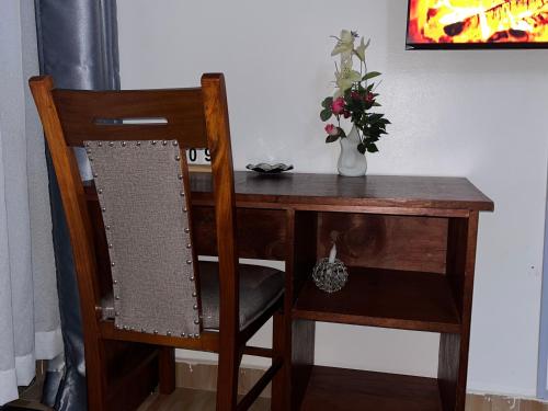 a wooden desk with a chair and a vase of flowers at Haven Studio in Ongata Rongai 