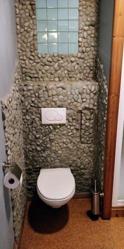 a bathroom with a stone wall with a toilet at Klik Klak Studio in Bornem