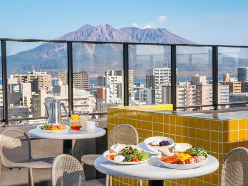 two tables with plates of food on a balcony at FAV LUX Kagoshima Tenmonkan in Kagoshima