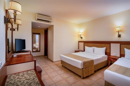 a hotel room with two beds and a flat screen tv at Ozlem Garden Hotel in Side
