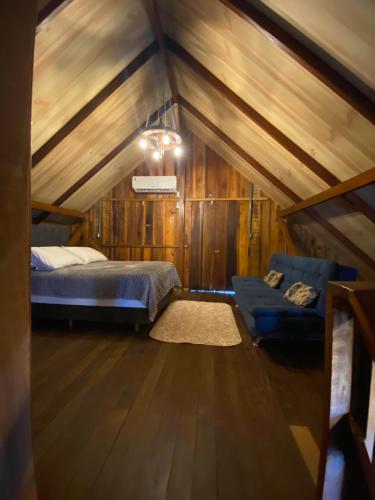a bedroom with a bed and a couch in a attic at Cabana Do Lago in Joinville