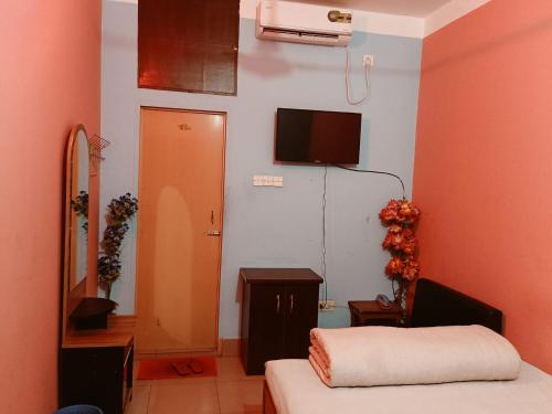a room with a bed and a tv on the wall at Green View Resthouse in Sreemangal