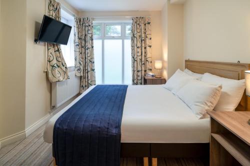 a bedroom with a bed and a window with a television at Carrington House Hotel in Bournemouth