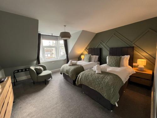 a hotel room with two beds and a chair at The Braeriach in Newtonmore