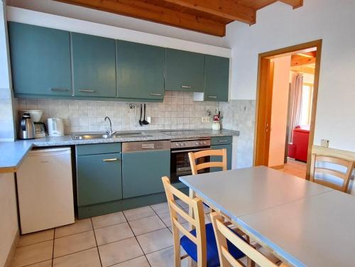 a kitchen with green cabinets and a table with chairs at Haus 23 Natur Ferienpark - Gemütlicher Urlaubsort für entspannte Tage im Grünen und in der Nähe von den Externsteinen in Nieheim