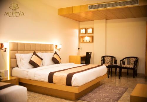a bedroom with a bed and a table and chairs at Hotel Aditya Residency in Bhopal