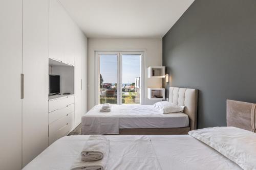 a bedroom with two beds and a tv and a window at Villa AMMA Pool & Jacuzzi by PikHost in Draç