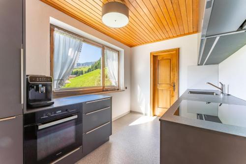 a kitchen with a stove and a sink and a window at Ferienhaus am Waldrand in Damuls