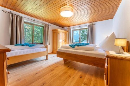 two beds in a room with wooden floors and windows at Ferienhaus am Waldrand in Damuls