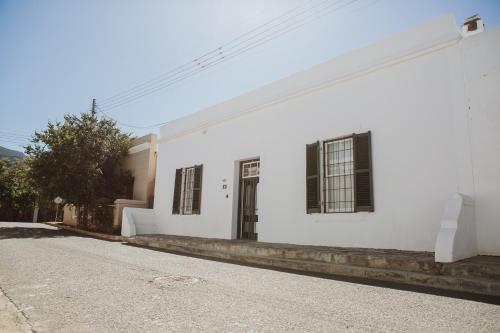 a white building with black windows and a street at Charming Historical Cottage in Graaff-Reinet